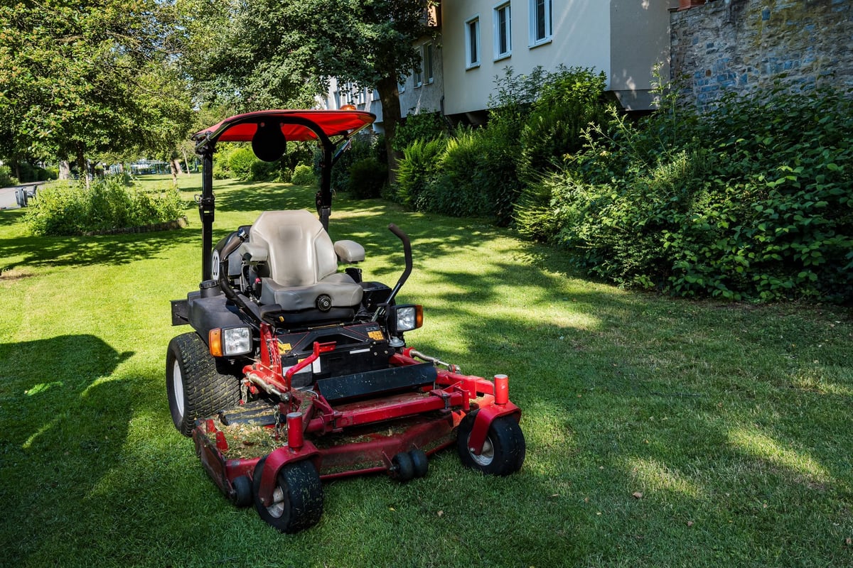 A riding mower is parked on freshly cut grass in a residential area